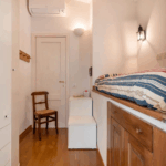 Camera Blu interior with bed nook, chair, and storage. Cozy room design.