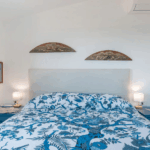 Camera Blu double bed. Bedroom with blue floral bedding, white walls, and blue nightstands.