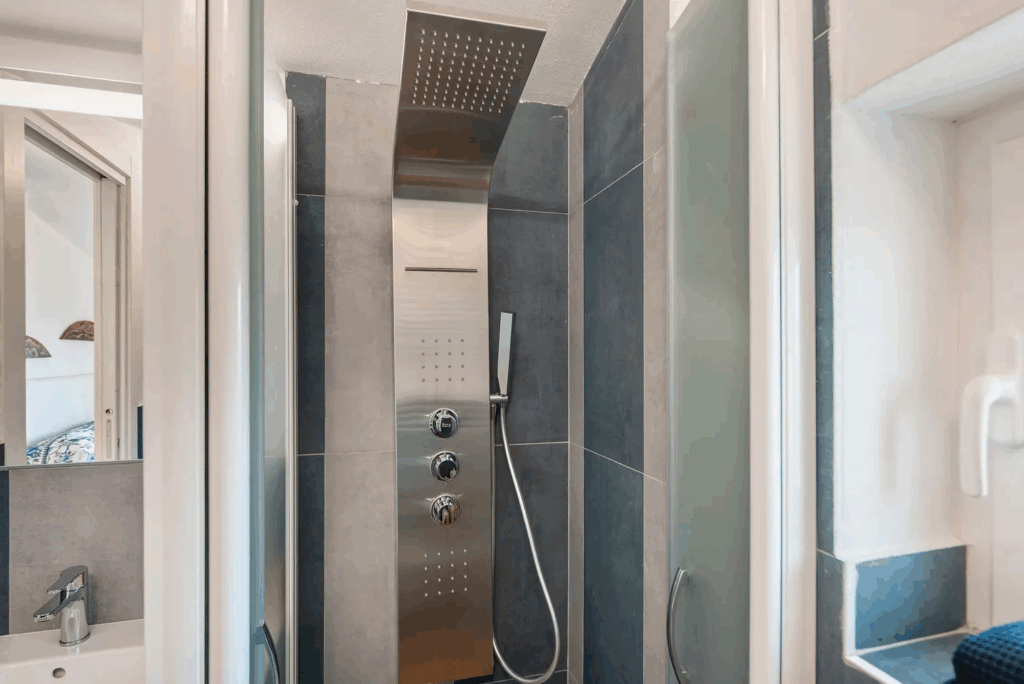 Camera Blu shower. Modern bathroom with stainless steel shower panel and glass door.