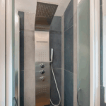 Camera Blu shower. Modern bathroom with stainless steel shower panel and glass door.