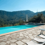 Casa di Pietra pool view. Swimming pool with mountain views and stone patio. Loungers for relaxation.